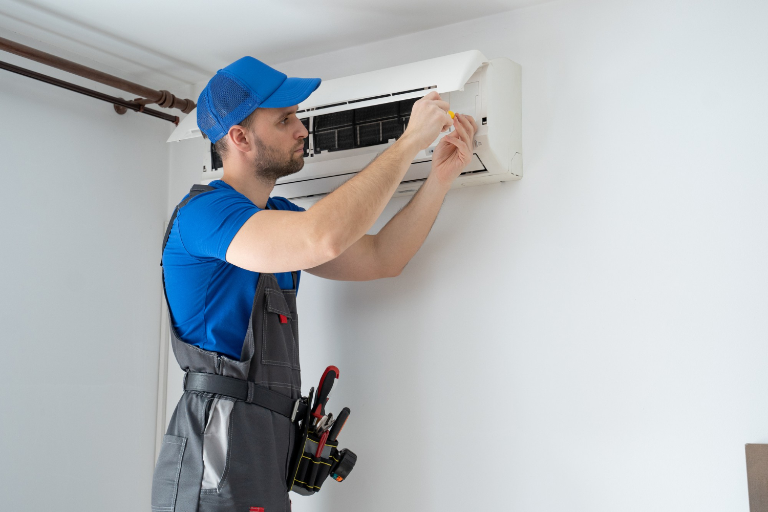 HVAC Blog 2 HVAC technician performing maintenance on a wall-mounted air conditioning unit in a residential setting, emphasizing service for Easton homeowners.