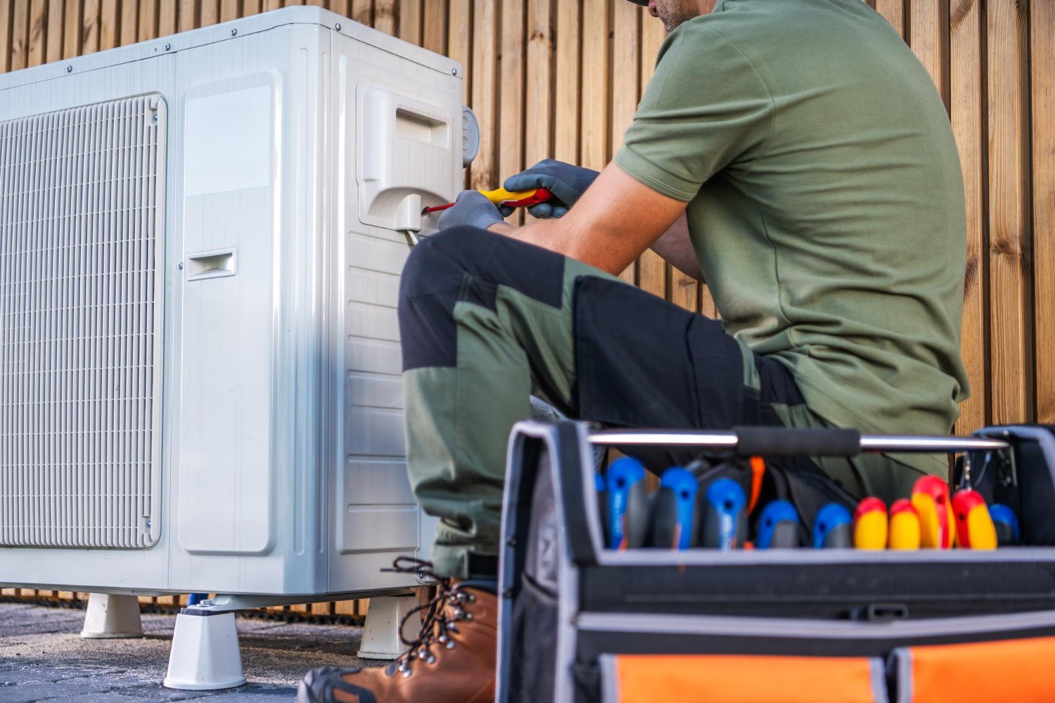 HVAC technician repairing a heat pump with tools in Easton, MD, emphasizing residential heating and cooling services.