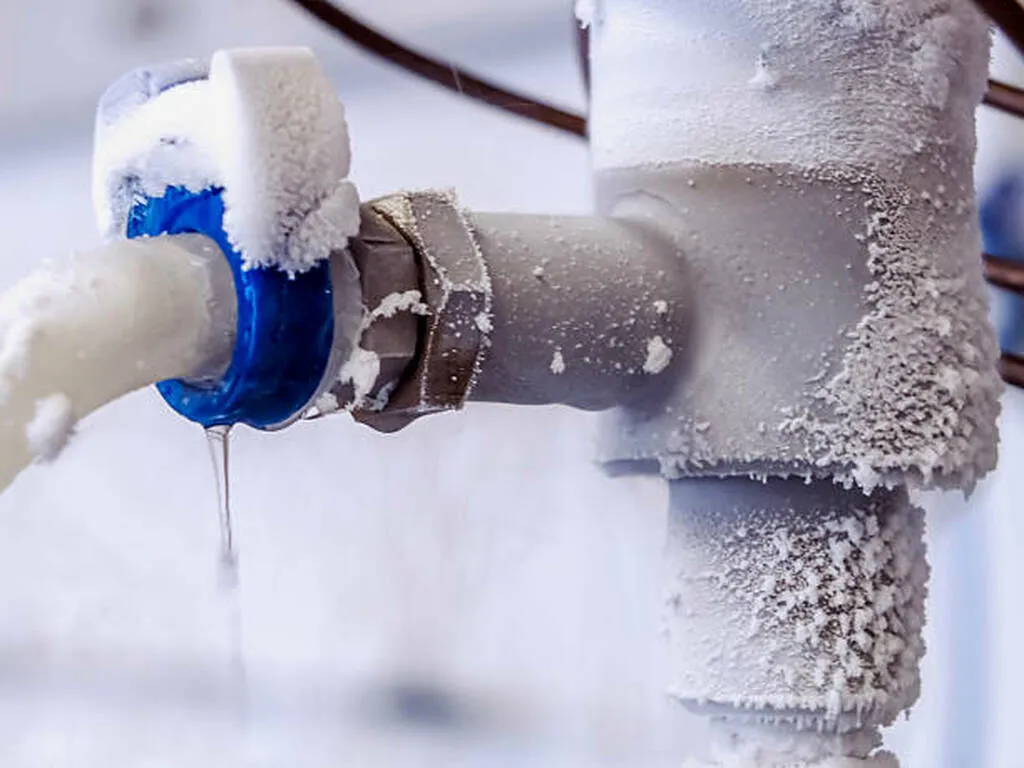 How to Prevent Frozen Pipes in Winter 2 Frozen outdoor faucet with ice buildup and dripping water, illustrating the risks of unprotected plumbing during winter.